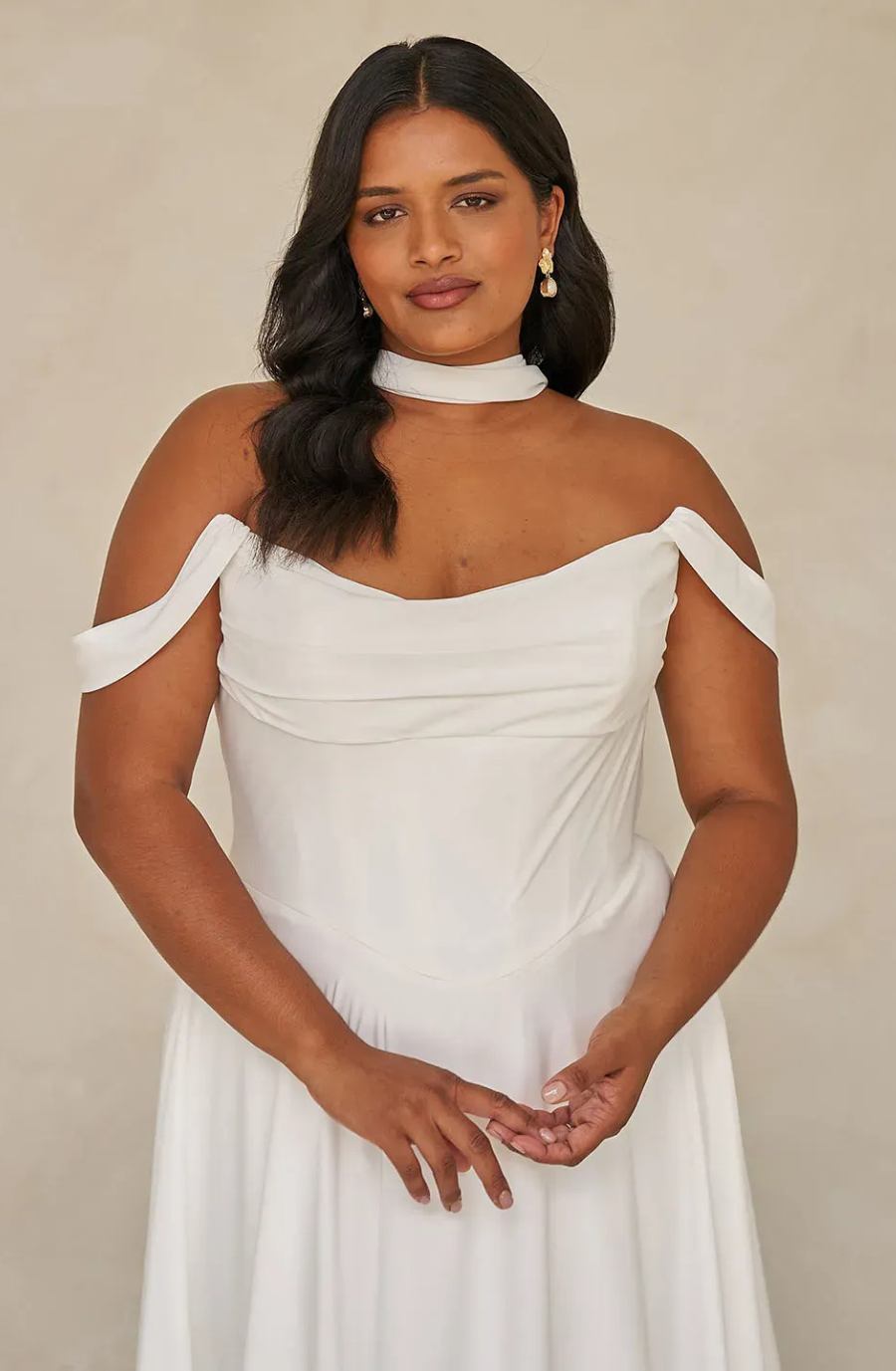model is wearing an off the shoulder plus size wedding dress